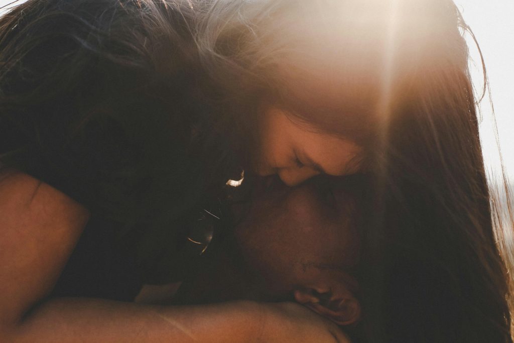 Женщина целует плечо мужа в мягком свете — как вернуть страсть в отношениях с мужем через нежность и доверие